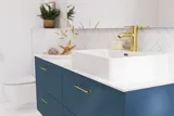 Baderomsinspirasjon med baderomsmøbler i moderne blå farge, elegant bordstående vask og stort firkantet speil med lys, hvite fiskebensfliser gir et stilfullt og klassisk uttrykk