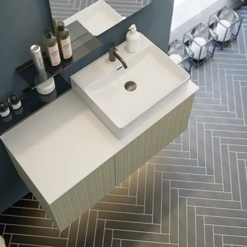 Baderom med skrått tak inspirasjon, beige baderomsmøbler med rifler, elegant benkeplate og firkantet bordstående servant, vakkert firkantet speil med stilige hyller, blå vegger, store vinduer og sort fiskebeinsgulv gir et lyst og urbant uttrykk.