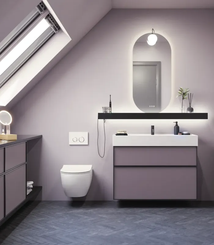 Baderom med skrå vegger inspirasjon, med baderomsmøbler i lilla med elegante rammefronter, flott oval speil med lampe, vakker og praktisk hylle, samt lilla malt vegg og grått fiskebeinsgulv som gir et elegant og moderne uttrykk.