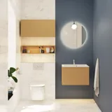 Lite, stilfullt baderom med mørkeblå vegger, myke gule baderomsmøbler med riller, og elegant rundt speil med lampe