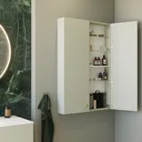 Stilfullt og luksuriøst baderom med myke grønne nyanser, et stort elegant rundt speil og et moderne, sofistikert grønt toalett