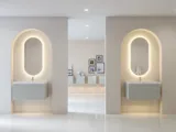 Stilfull og moderne baderomsinspirasjon med ovale speil med lysstyring, steinvasker og servantskap med fine og elegante riller i en minimalistisk design, badet har en lys og luftig atmosfære med elegant belysning og raffinerte detaljer