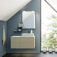 Baderom med skrått tak inspirasjon, beige baderomsmøbler med rifler, elegant benkeplate og firkantet bordstående servant, vakkert firkantet speil med stilige hyller, blå vegger, store vinduer og sort fiskebeinsgulv gir et lyst og urbant uttrykk.