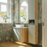 Baderomsinspirasjon med baderomsmøbler i grønn spesialfarge med sider i naturlig eik, elegante riller, stilfull benkeplate med romantisk oval bordstående servant, vakkert ovalt speil, gir sammen med blomstrete tapet et yndefullt, vintage retro uttrykk.