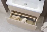Liten baderomsinspirasjon med servantskap og overskap over toalett i beige spesialfarge, elegant speilskap med integrert lys, de lyse fargene og hvite gardinet skaper en romantisk og feminin atmosfære.