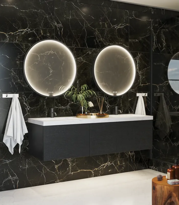 Elegant og moderne baderomsinspirasjon med mørke marmorerte vegger, runde opplyste speil med svart ramme, vegghengt servantskap med dobbeltvask og en romslig dusjniche