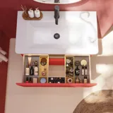 Baderomsinspirasjon med røde vegger, mykt formede røde servantskap og høyskap, elegant hvit servant og et vakkert ovalt speil med lys som sammen med de naturlige omgivelsene skaper et vintage uttrykk