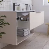 Baderomsinspirasjon med rosa servantskap med elegante riller og vakker vask, hvite fliser på veggene og store beige fliser på gulvet skaper et romantisk og feminint uttrykk.