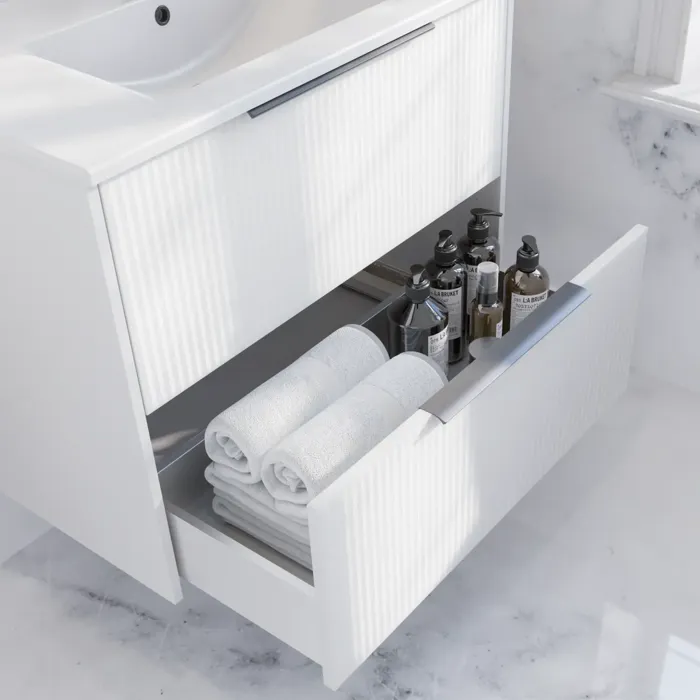 Baderomsinspirasjon med hvit servantskap med elegante riller og vakker servant, hvite marmorvegger og -gulv for et lyst og moderne uttrykk.