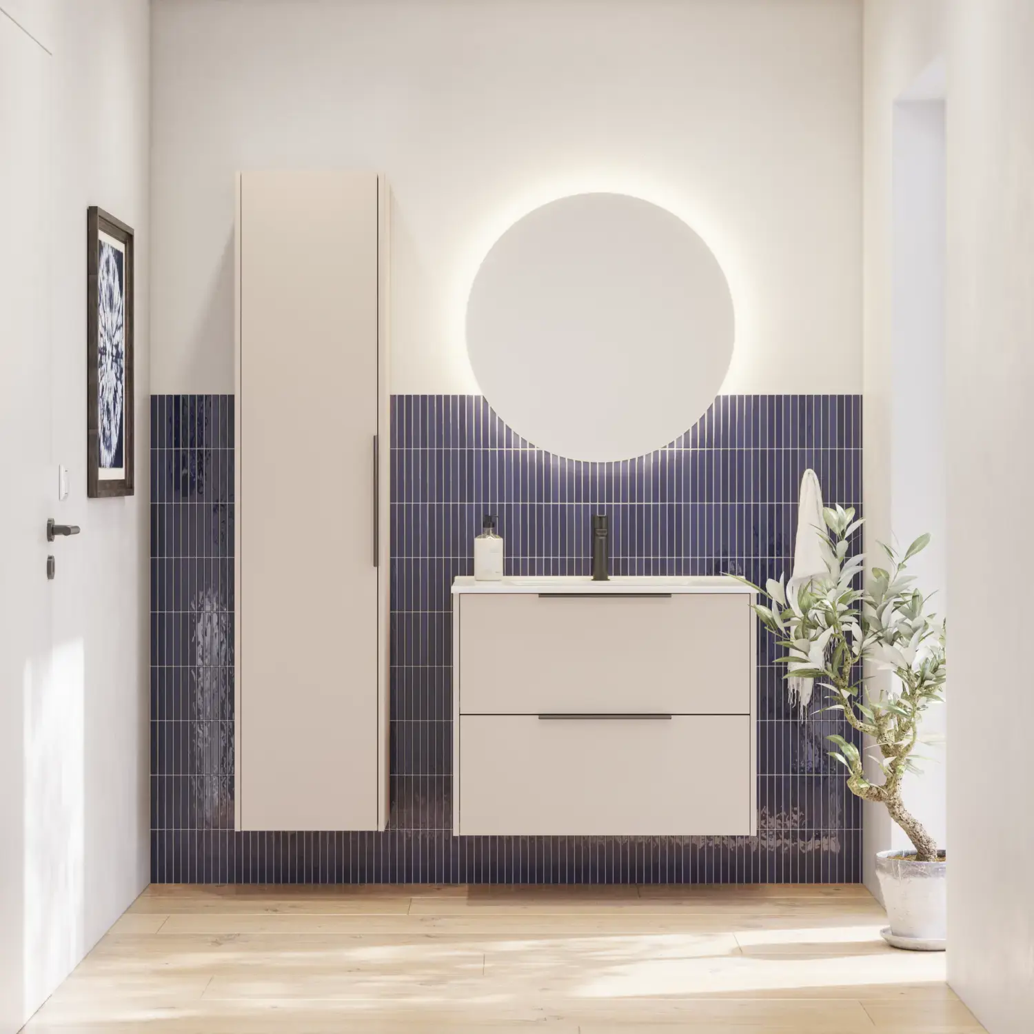 Baderomsinspirasjon med avlange blå fliser, elegant beige servantskap og høyskap med svarte, minimalistiske og avlange håndtak og et rundt speil med lys som gir et vakkert og kontrastfylt uttrykk.