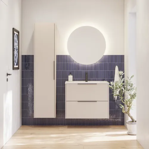 Baderomsinspirasjon med avlange blå fliser, elegant beige servantskap og høyskap med svarte, minimalistiske og avlange håndtak og et rundt speil med lys som gir et vakkert og kontrastfylt uttrykk.
