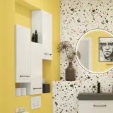 Liten baderomsinspirasjon med hvitt vaskeskap med svart grep og svart elegant vask, vakkert rundt speil med svart kant, forskjøvet plasserte overskap samt terrazzo vegg og gulv og gule vegger gir et modig og moderne uttrykk.