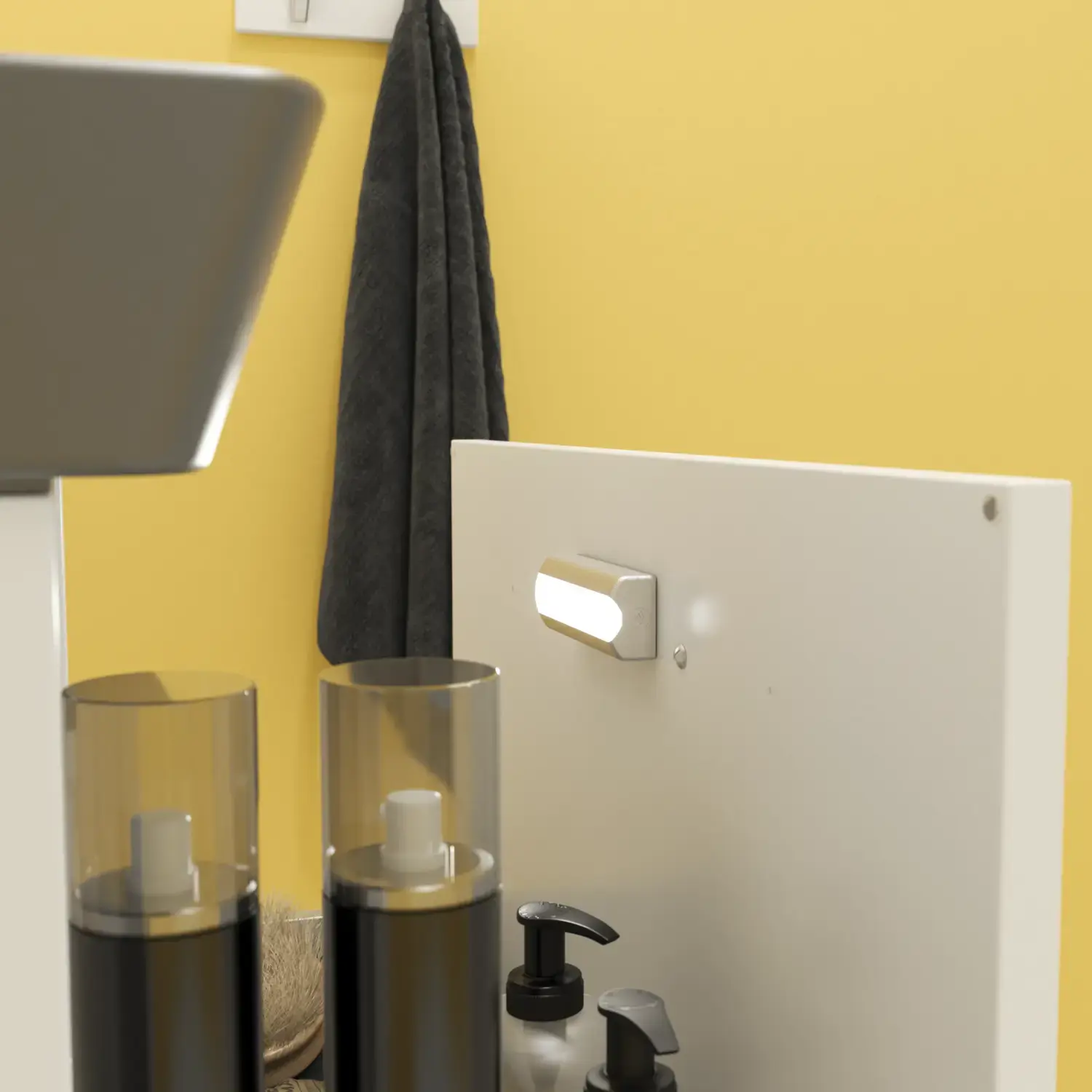 Liten baderomsinspirasjon med hvitt vaskeskap med svart grep og svart elegant vask, vakkert rundt speil med svart kant, forskjøvet plasserte overskap samt terrazzo vegg og gulv og gule vegger gir et modig og moderne uttrykk.