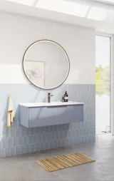 Baderomsinspirasjon med avlange lyseblå fliser og betongulv, elegant vaskeskap i lys blå med vakre smale striper, stilren og tynn vask, dobbelt høyskap med smale striper, samt minimalistisk rundt speil med svart kant og lys.