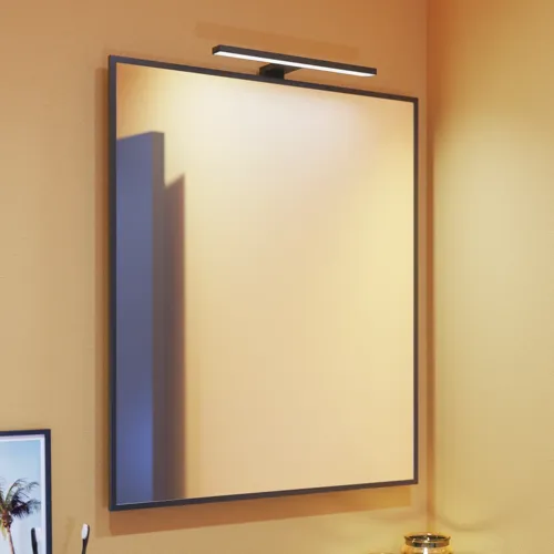 Liten baderomsinspirasjon med skrå og varme gule vegger, og minimalistisk firkantet speil med stilren svart kant, samt elegant lampe til speilet, som tilfører et snev av eleganse til baderommet ditt.