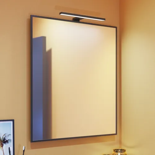 Liten baderomsinspirasjon med skrå og varme gule vegger, og minimalistisk firkantet speil med stilren svart kant, samt elegant lampe til speilet, som tilfører et snev av eleganse til baderommet ditt.